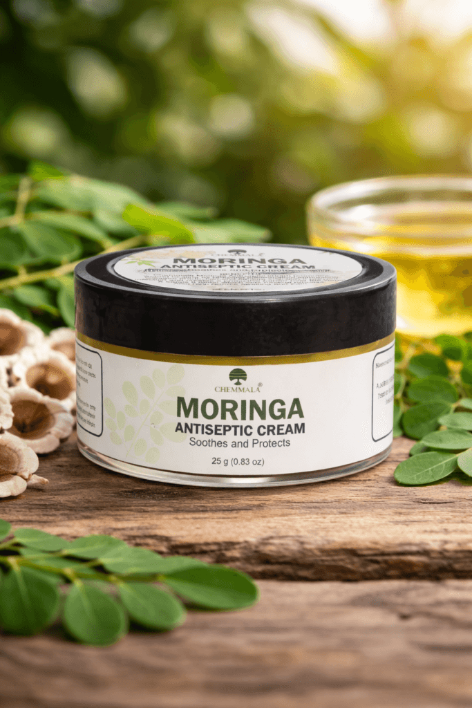 Chemmala moringa antiseptic cream jar placed with fresh moringa leaves and natural ingredients in a herbal skincare setting
